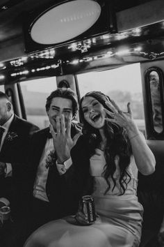 a man and woman sitting on a bus with their hands up in the air as they laugh