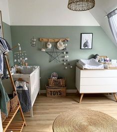 a baby's room with green walls and white furniture