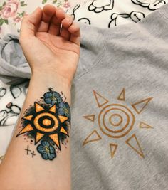 a person with a sun tattoo on their arm and the other hand is holding an object