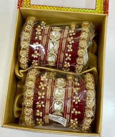 two red and gold bracelets in a box on a white table with an orange ribbon