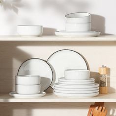 white dishes and wooden utensils sit on a shelf