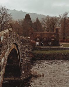 a stone bridge over a river next to a house