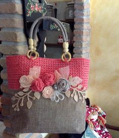 a handbag made out of fabric with flowers on the front and side, hanging from a hook