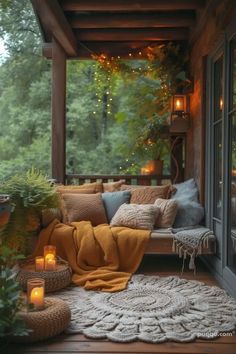 a porch covered in lots of pillows and blankets with candles on the floor next to it