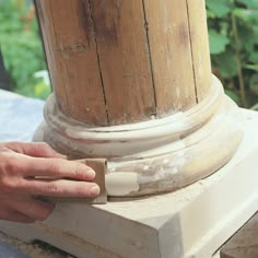 a person is sanding the base of a wooden pillar