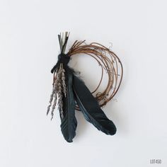 a feather and some twigs on a white surface