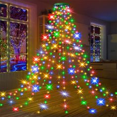 a brightly lit christmas tree sitting on top of a wooden floor