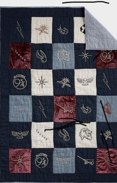 a quilted blanket with various patches and symbols on it, along with an knitting needle