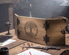 a wooden box sitting on top of a table filled with writing and other items next to a candle