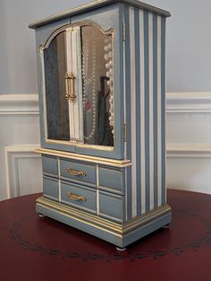 a blue and white striped cabinet on top of a red table with gold trimmings