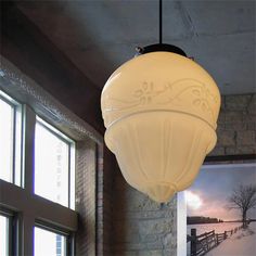 a white light hanging from the ceiling in a room with brick walls and windows on both sides