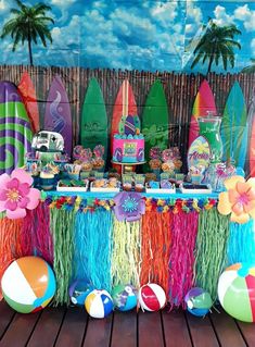 a table topped with lots of colorful decorations and beach balls on top of a wooden floor