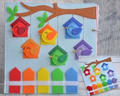 a felt board with birds and houses hanging from it's sides on a wooden table