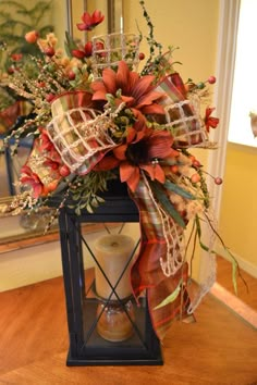 a vase filled with red flowers on top of a wooden table next to a mirror