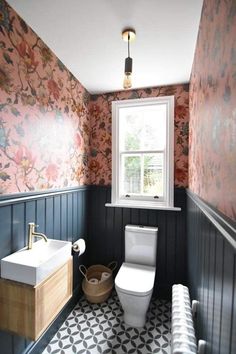 a bathroom with floral wallpaper and black and white tile flooring, along with a window