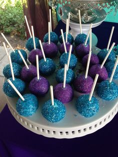 blue and purple cake pops sitting on top of a white plate