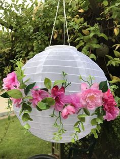 a white paper lantern with pink flowers hanging from it