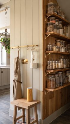 a wooden shelf filled with lots of jars and containers next to a wall mounted spice rack