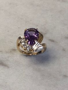 This beautiful 14kt Yellow Gold Lady's Diamond and Amethyst Ring consists of a 10mm x 15mm Genuine Pear Shape Amethyst Gemstone 5.00ct approx total weight and 4 diamond accents .05ct approx total weight all prong set in a fashion swirl solid mounting. Finger size 6 1/2 which can be resized. Amethyst is the Birthstone for February. This item would Retail for $1,250.00 Fine Jewelry Teardrop Purple Ring, Fine Jewelry Purple Teardrop Ring, Purple Teardrop Fine Jewelry Ring, Purple Teardrop Amethyst Ring For Anniversary, Purple Pear-shaped Ring With Prong Setting, Elegant Teardrop Amethyst Ring, Pear-shaped Purple Amethyst Ring With Prong Setting, Elegant Teardrop Purple Amethyst Ring, Purple Pear-shaped Amethyst Ring With Prong Setting