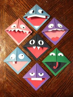 four different colored origami animals on a wooden table with eyes, mouths and noses