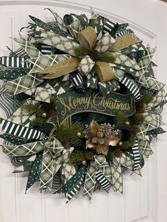 a christmas wreath on the front door with green and gold ribbons hanging from it's sides