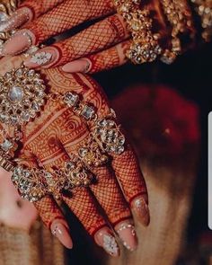 two hands with gold and diamond jewelry on their palms, both holding onto each other