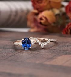 a blue and white diamond ring sitting on top of a wooden table next to flowers