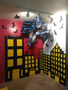 a batman themed room with black and yellow decorations on the walls, bats hanging from the ceiling