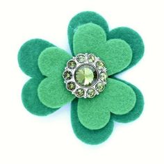 a green flower brooch sitting on top of a white surface