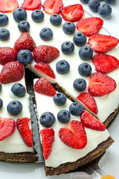 a cake with strawberries and blueberries on it is cut in half to show the filling