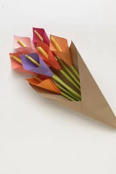 an origami flower bouquet is displayed on a white surface with long stems sticking out of it