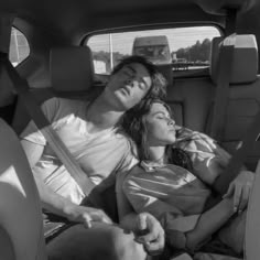 a man and woman laying in the back seat of a car