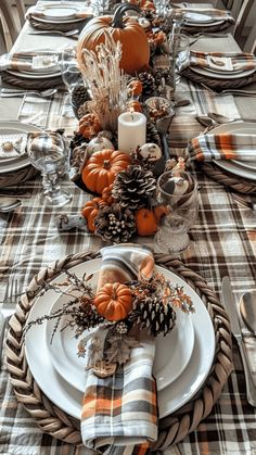 the table is set for thanksgiving dinner with pumpkins, pine cones and plaid napkins