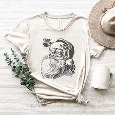 Vintage Santa Tee, Merry Christmas Shirt, Black Ink Santa, Classic Christmas Tee. SIZE UP for an OVERSIZED look (see size chart in listing photos). Looking for more Christmas and Winter themed apparel? Check these out: https://www.etsy.com/shop/TheGraphicPeach?ref=seller-platform-mcnav§ion_id=30496778 Our shop uses direct-to-garment printing to make our products. The design ink is sprayed on, then allowed to soak into the fibers of the garment. This process yields fine quality prints and a smoot Holiday Shirts For Women, Santa Tee, Graphic Tee Outfits, Santa Shirts, Merry Christmas Shirts, Tees For Women, Christmas Tees, Holiday Shirts, Vintage Santas