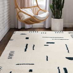 a white rug with blue and black designs on it in front of a window next to a chair