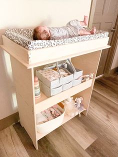 a baby laying on top of a wooden shelf