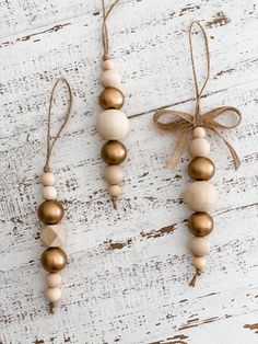 three wooden beaded ornaments hanging from twine on white wood planks with burlap ribbon