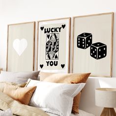 three framed pictures on the wall above a bed with two dices in front of them