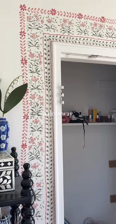 an open door leading into a room with white walls and red flowers on the wall