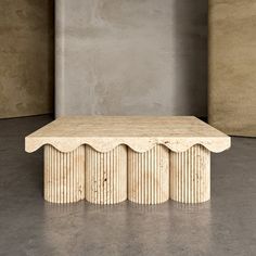 a table with scalloped edges in front of a gray wall and concrete floor