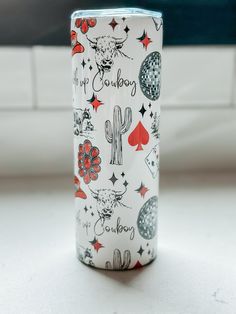 a white can with red and black designs on it sitting on a table next to a couch