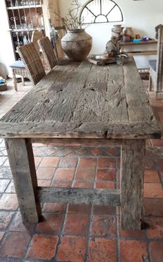 an old wooden table with chairs around it in a room filled with brick flooring