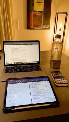 an open laptop computer sitting on top of a wooden desk next to a cell phone