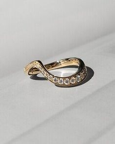 a gold ring with diamonds on it sitting on top of a white surface, in the middle