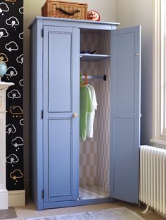 a blue armoire sitting next to a wall with a basket on top of it