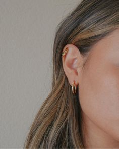 a close up of a person with ear piercings on their ears and wearing gold jewelry