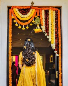 a woman standing in front of a doorway decorated with flowers and garlands on it