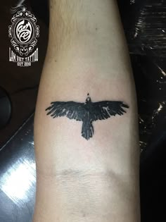 a black bird tattoo on the arm