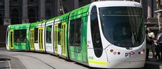 a green and white tram is on the tracks