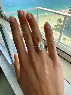 a woman's hand with a diamond ring on it, looking out the window